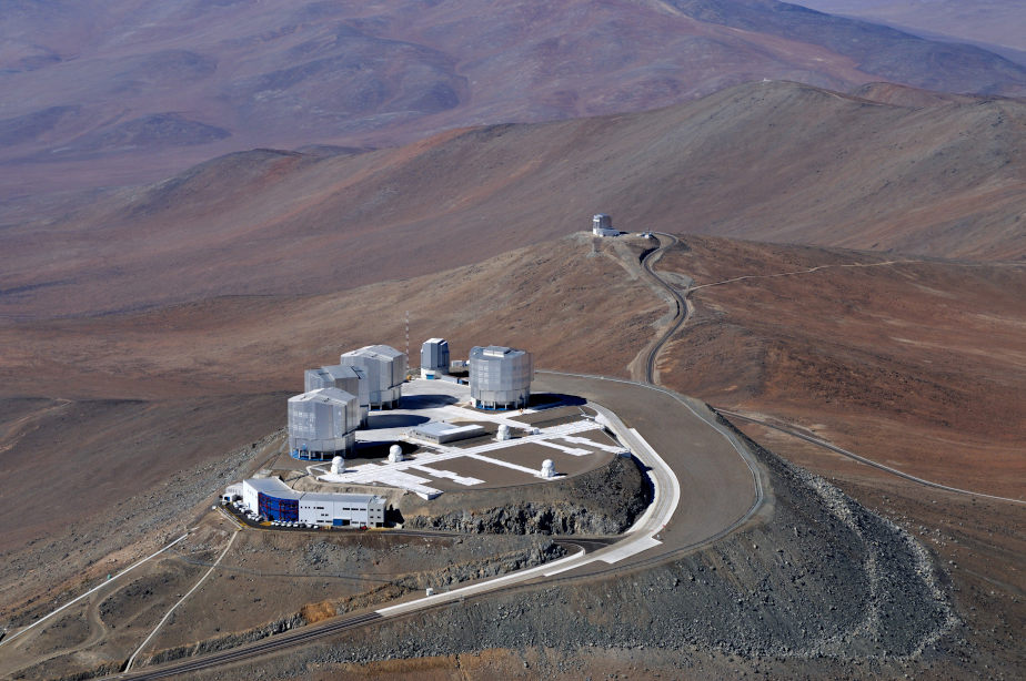 The colored image shows an astronomical research station on a mountain, which is surrounded by a desert landscape.