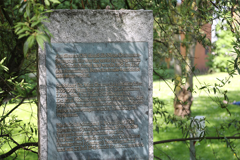 The photo shows the memorial to the New Dammtor Synagogue. It is an upright stone slab with an inscribed metal surface.